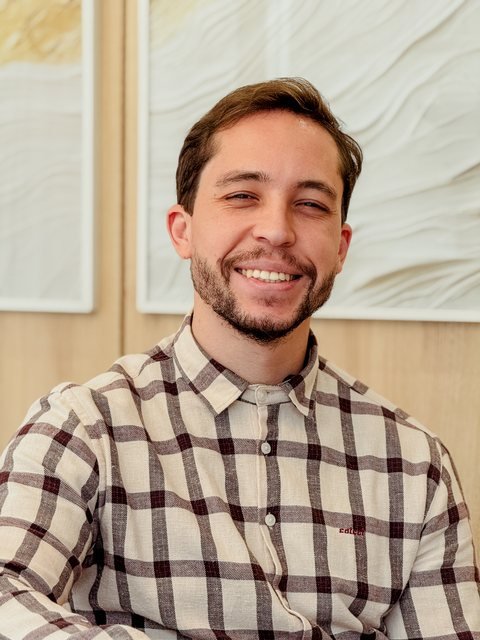 Matheus Vieira da Cunha, psicólogo e psicanalista, sorrindo, de camisa xadrez